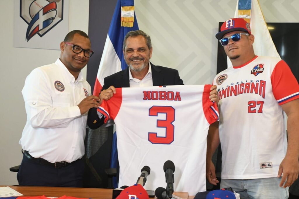 Ambiorix Vidal y el dirigente del equipo, Edward Rodríguez (Pichulo), entregan una camiseta al Comisionado Nacional de Béisbol, Junior Noboa. 